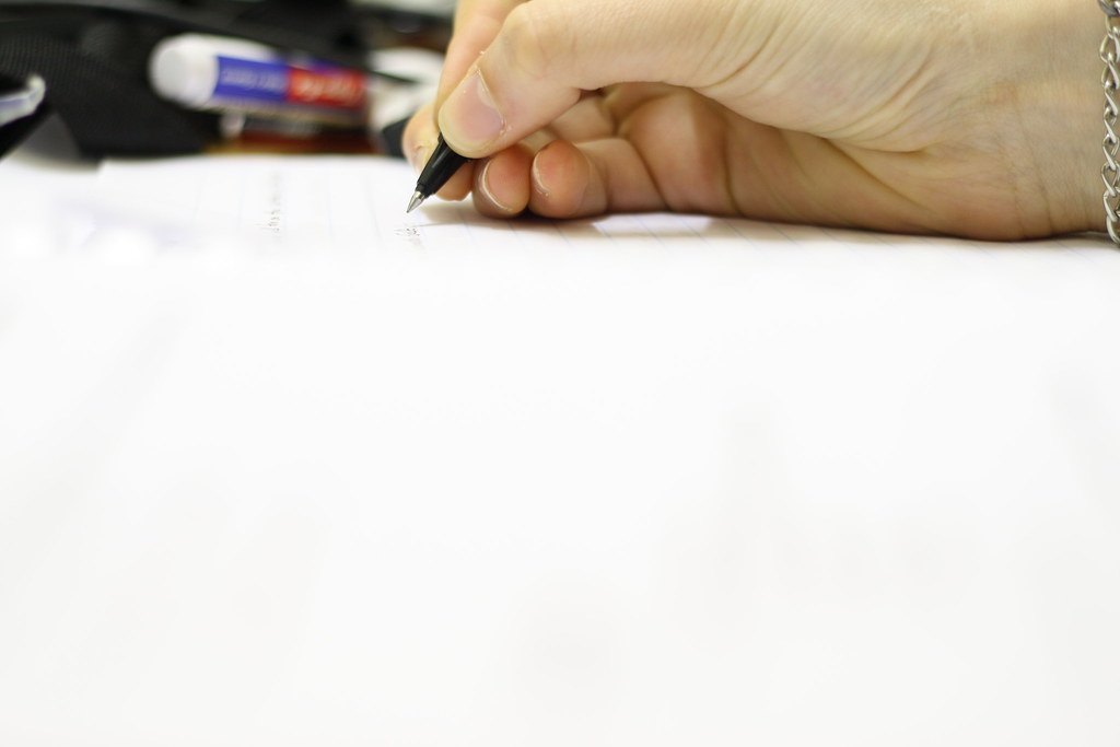 Main écrivant une note supplémentaire au stylo pour simuler son impact sur la moyenne