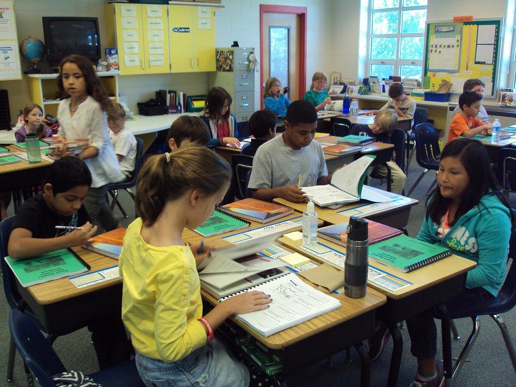 Élèves en classe travaillant sur leurs cahiers, illustrant la notation par compétences